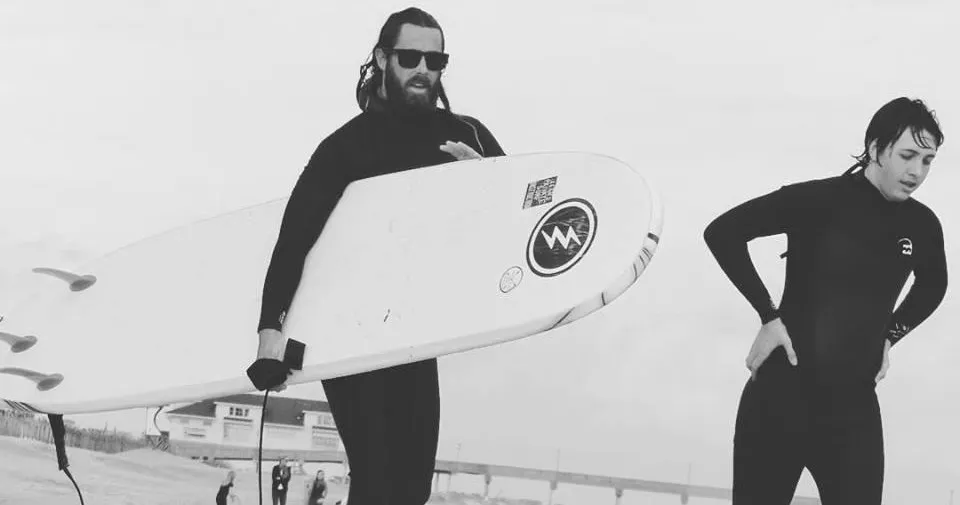 Guys in wetsuits surfing